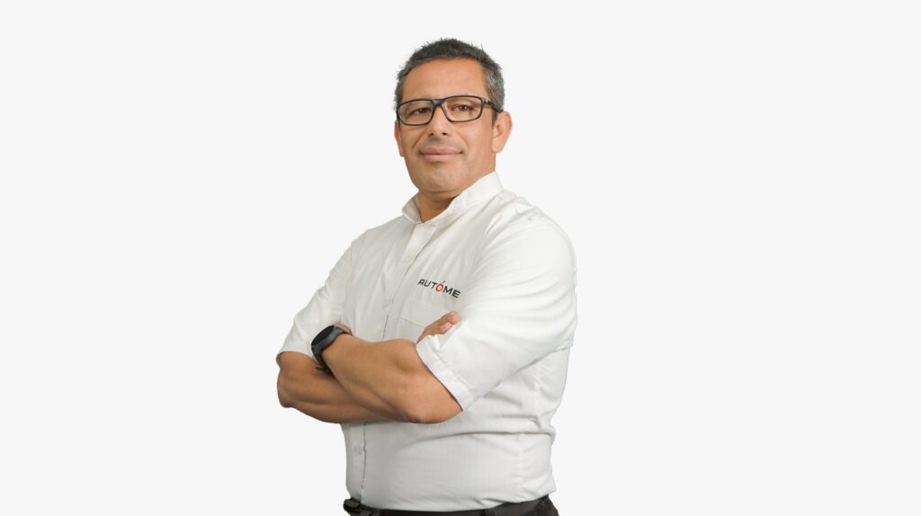 Portrait of a man in a white shirt with the Autome logo, arms crossed, looking at the camera.