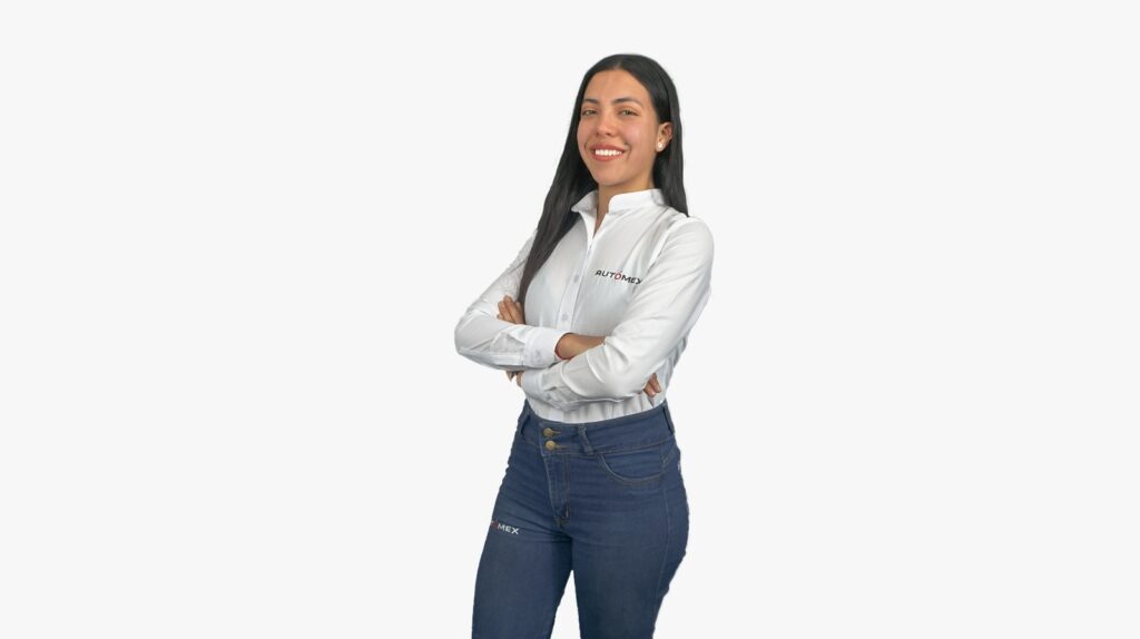 Portrait of a smiling woman with arms crossed, wearing a white shirt with a company logo and blue jeans, standing against a light background.
