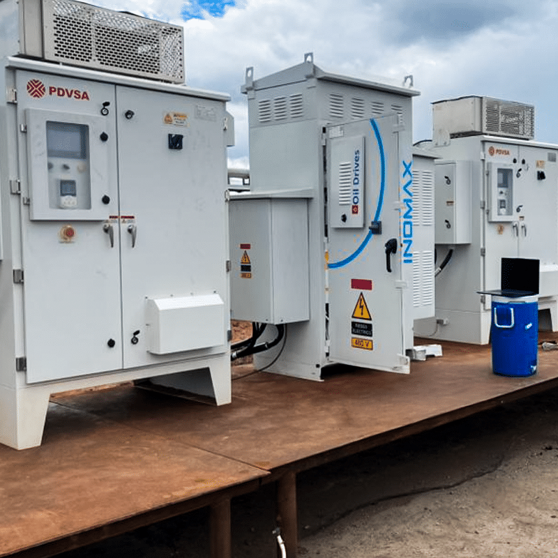 Outdoor row of large electrical switchgear cabinets on a metal platform, PDVSA branding and warning labels visible.